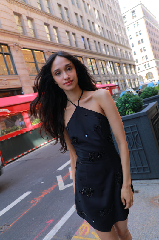 Black halter mini dress with floral embellishments and fitted silhouette
