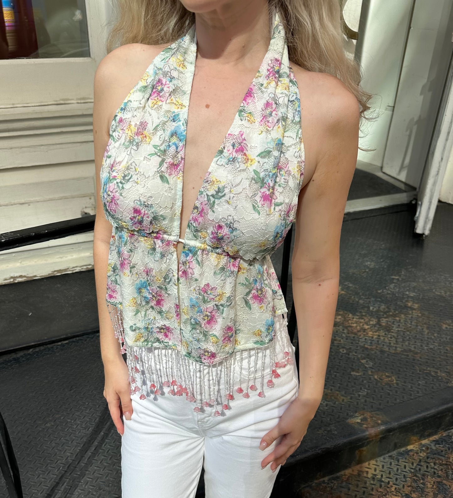 Floral halter top with lace-like fabric, V neckline, and tassel hem detail