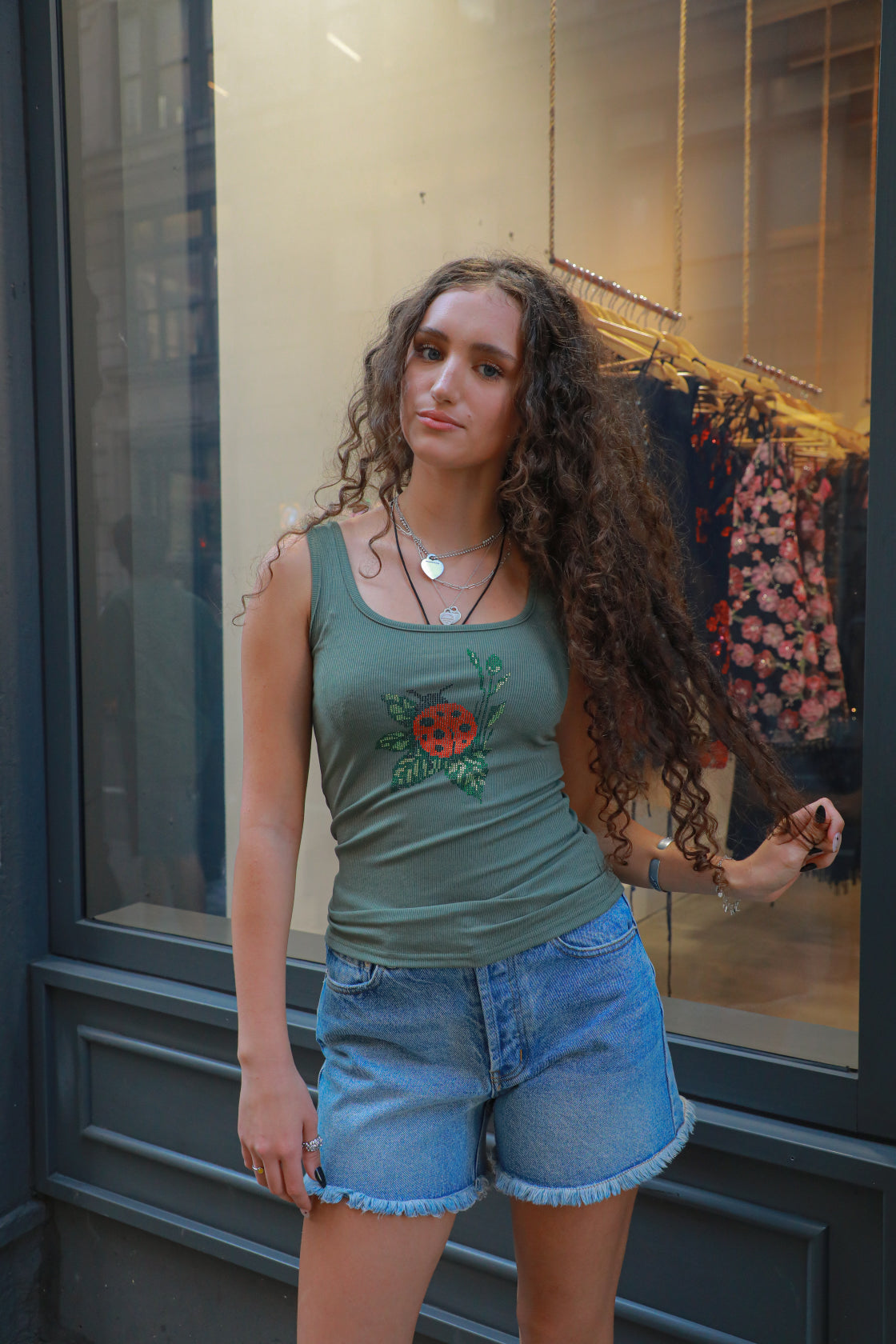 Olive green ribbed tank top with rhinestone ladybug graphic at center chest