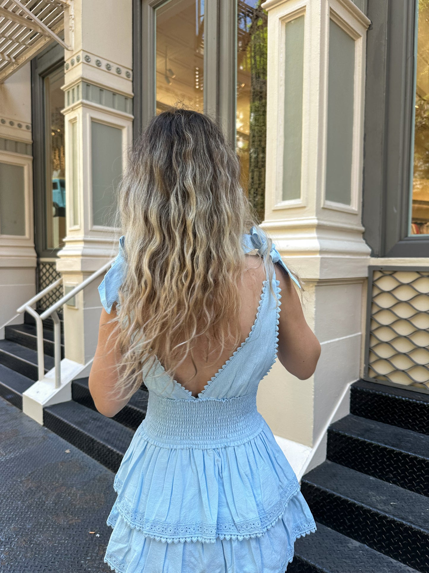 Back view of light blue mini dress with smocked waist and lace-trim tiered skirt
