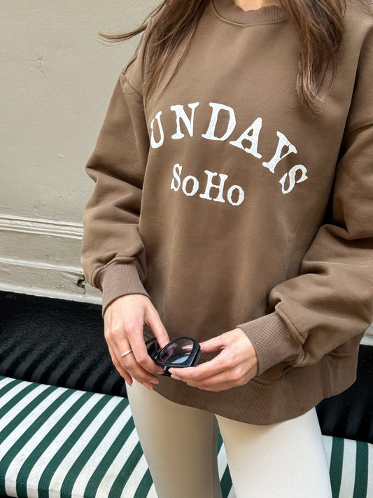 Brown crewneck sweatshirt with white 'SUNDAY' and 'Soho' graphic on front.
