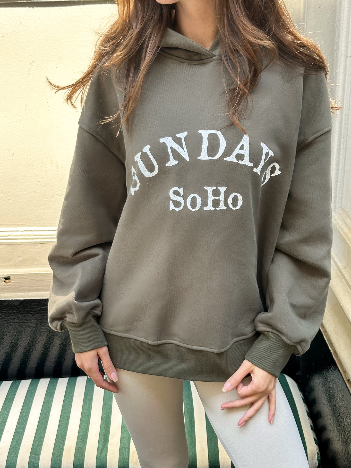 Gray hoodie with hood and front pocket, 'SUNDAY SoHo' graphic print on chest